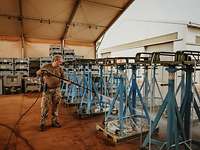 Ein Soldat reinigt Metallgestelle mit einem Hochdruckreiniger
