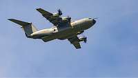 A large aircraft flies with the cargo ramp open.