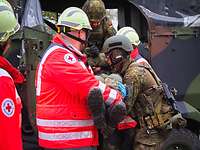 Soldatinnen und Soldaten sowie Kräfte des Deutschen Roten Kreuzes laden einen Verwundeten in ein Fahrzeug.