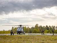Kriegsgefangene werden von Soldaten zu einem Hubschrauber gebracht. Weitere Soldaten sichern die Kameraden.