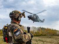 Ein Hubschrauber ist im Landeanflug, im Vordergrund steht ein Soldat.