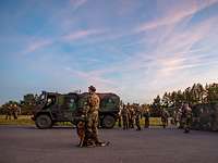 Mehrere Soldatinnen und Soldaten sowie ein Diensthund stehen um das Bundeswehr-Fahrzeug YAK.