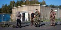 militärisch gekleidete Personen stehen vor einem Gebäude