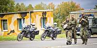 3 Soldaten, im Hintergrund zwei Motorräder und ein Geländefahrzeug der Feldjäger