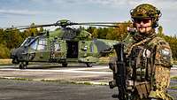 Soldat steht vor Hubschrauber.