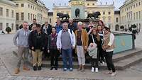 Mehrere Personen stehen vor den historischen Gemäuern des Schlosses Ludwigsburg.