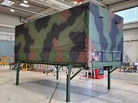 Swap body Curtain-sided swap body with camouflage paint on green stilts.