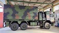 Truck with swap body A truck with green, black and brown camouflage paint standing in a hangar.