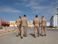 Vier Piloten laufen mit dem Rücken zur Kamera nebeneinader und reden.