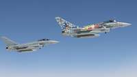 Zwei Eurofighter fliegen vor blauen Himmel nebeneinander.