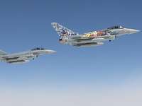 Zwei Eurofighter fliegen vor blauen Himmel nebeneinander.