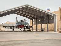 Ein Eurofighter steht in einem Shelter. Daneben weht auf einem Hügel die Fahne Mecklenburg-Vorpommerns.