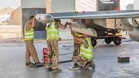 Man sieht einen Flügel vom Eurofighter darunter arbeiten Mechaniker an einem Bauteil.