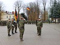 Die Übergabe ist vollzogen Zwei Soldaten grüßen sich militärisch. Links davon steht die Truppenfahne mit zwei Begleitoffizieren.