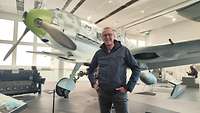 Ein Mann steht vor einem Jagdflugzeug.
