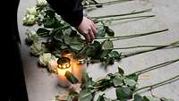 Trauer Eine Hand berührt weiße Rosen.