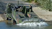 Ein Motorboot gleitet vom Heck eines Brückentransporters ins Wasser.