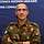 Ein Mann in Uniform steht vor einer blauen Leinwand
