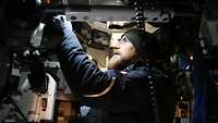 Ein Soldat schaut sich technische Anlagen im Panzerturm an.