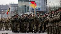 Zahlreiche Soldaten verschiedener Nationen marschieren in einer Formation auf der Paradestraße. 