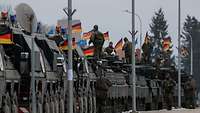 Mehrere gepanzerte Gefechtsfahrzeuge stehen aufgereiht hintereinander, darauf stehen Soldaten.