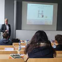 Jugendliche hören einem Dozenten in einer Vorlesung aufmerksam zu.