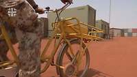 Ein Soldat fährt auf einem Postfahrrad durch das Camp Castor.