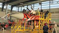 Einige Menschen stehen auf einem gelben Treppenaufgang zum Cockpit des Eurofighters.