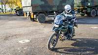 Ein Soldat fährt mit einem Motorrad über einen Platz.