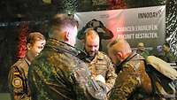 Vier Soldaten in Uniform stehen vor einem Plakat des Innoday´s