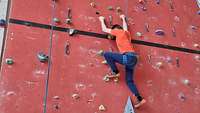 Ein Mann klettert eine Kletterwand hinauf.