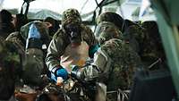 Mehrere Soldatinnen und Soldaten behandeln zwei verwundete Personen und untersuchen sie auf weitere Verletzungen