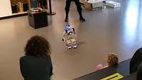 Mehrere Menschen betrachten einen 60cm großen Roboter.