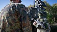 Ein Deutscher Soldat unterhält sich mit einem bewaffneten litauischen Soldaten. 
