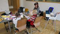 Eine Kinderbetreuerin bastelt mit den Kindern.