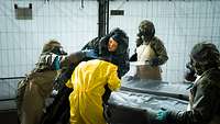 Four soldiers in protective suits treat a contaminated person