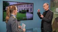 Eine Soldatin interviewt einen Mann vor einem Monitor in einem Studio