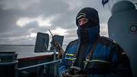 Ein Soldat steht in der Nock. Es schneit und der Soldat ist bis auf die Augen vermummt.