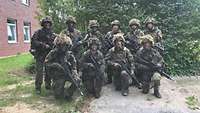 Zehn Soldaten stehen oder knien für ein Gruppenbild zusammen.