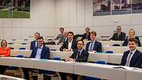 Der Staatssekretär sitzt im Hörsaal zwischen mehreren Studenten.