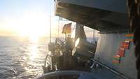 Das Oberdeck der Korvette in der Abendsonne. Im Wind weht die deutsche Flagge.