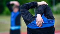 Mann in Sportkleidung dehnt Arme über Kopf