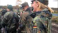 Mehrere Soldatinnen und Soldaten stehen beisammen auf einem Truppenübungsplatz