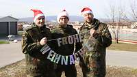 Drei Soldaten stehen nebeneinander und halten eine Weihnachtsgirlande in der Hand.