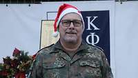 Ein Soldat mit einer Weihnachtsmütze steht vor einem Gebäude.
