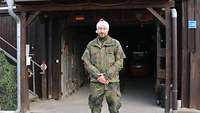 Ein Soldat mit Weihnachtsmütze steht vor einem Garageneingang eines Gebäudes.