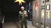 Ein Soldat mit Weihnachtsmütze hält ein Lebkuchenhaus in der Hand und steht unter einem Weihnachtsstern.