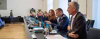 Männer und Frauen sitzen an einem langen Konferenztisch