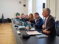 Männer und Frauen sitzen an einem langen Konferenztisch