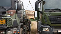 Eine Palette wird von einem niederländischen Lkw auf einen deutschen Lkw gehoben.